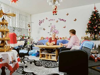 Innenaufnahme: Zwei Frauen sitzen in einem weihnachtlich geschmückten Wohnzimmer.