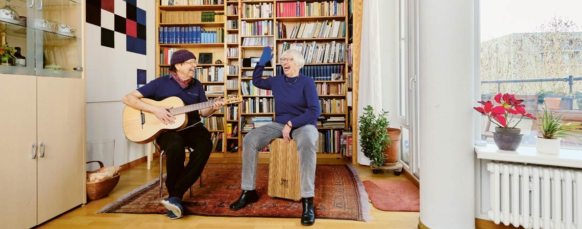 Innenaufnahme: Ein älterer Mann und eine ältere Frau machen in ihrem Wohnzimmer Musik.