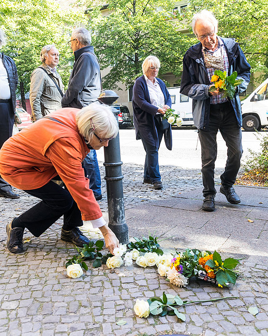 Bei der Gedenkfeier legen Bewohner*innen und Mitglieder der Stolpersteingruppe Alt-Pankow Blumen nieder