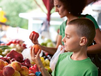 Kind an einem Obststand auf dem Wochenmarkt