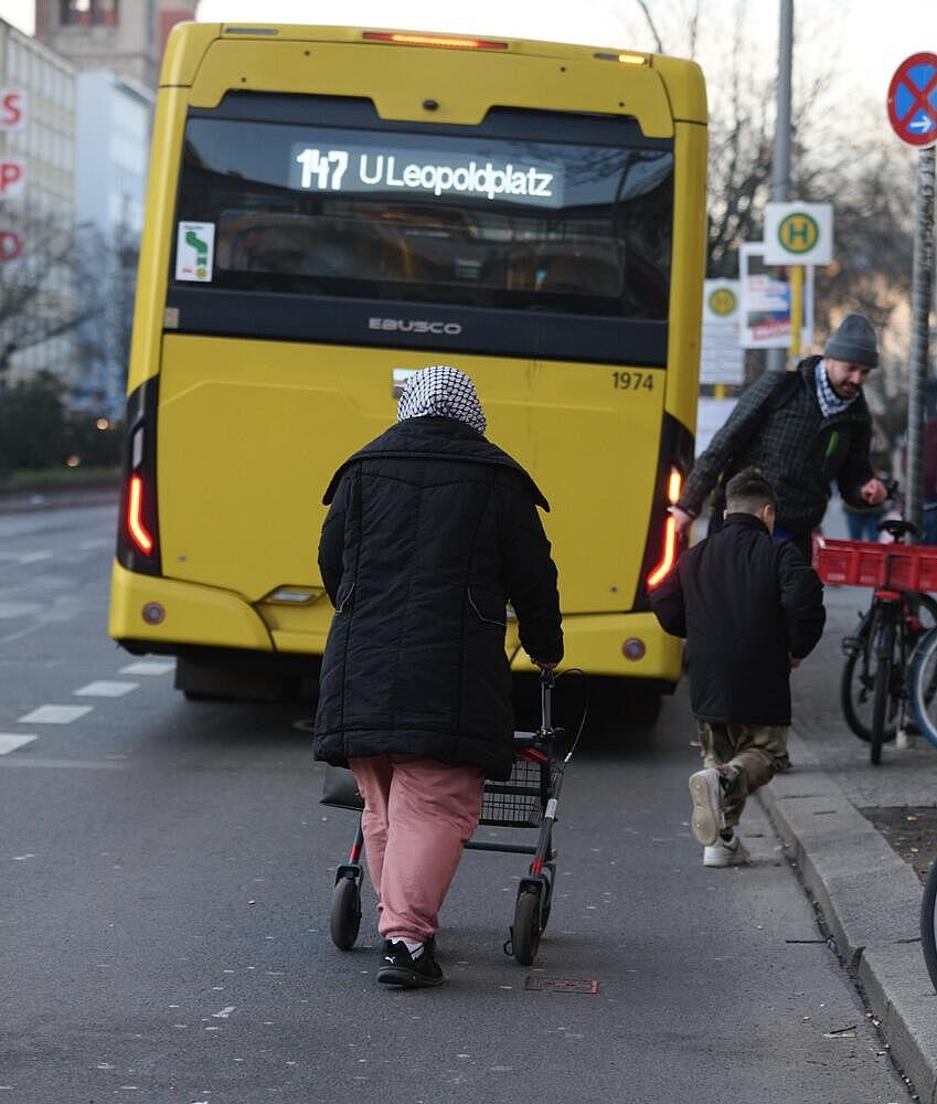 Personen versuchen den haltenden Bus zu erreichen