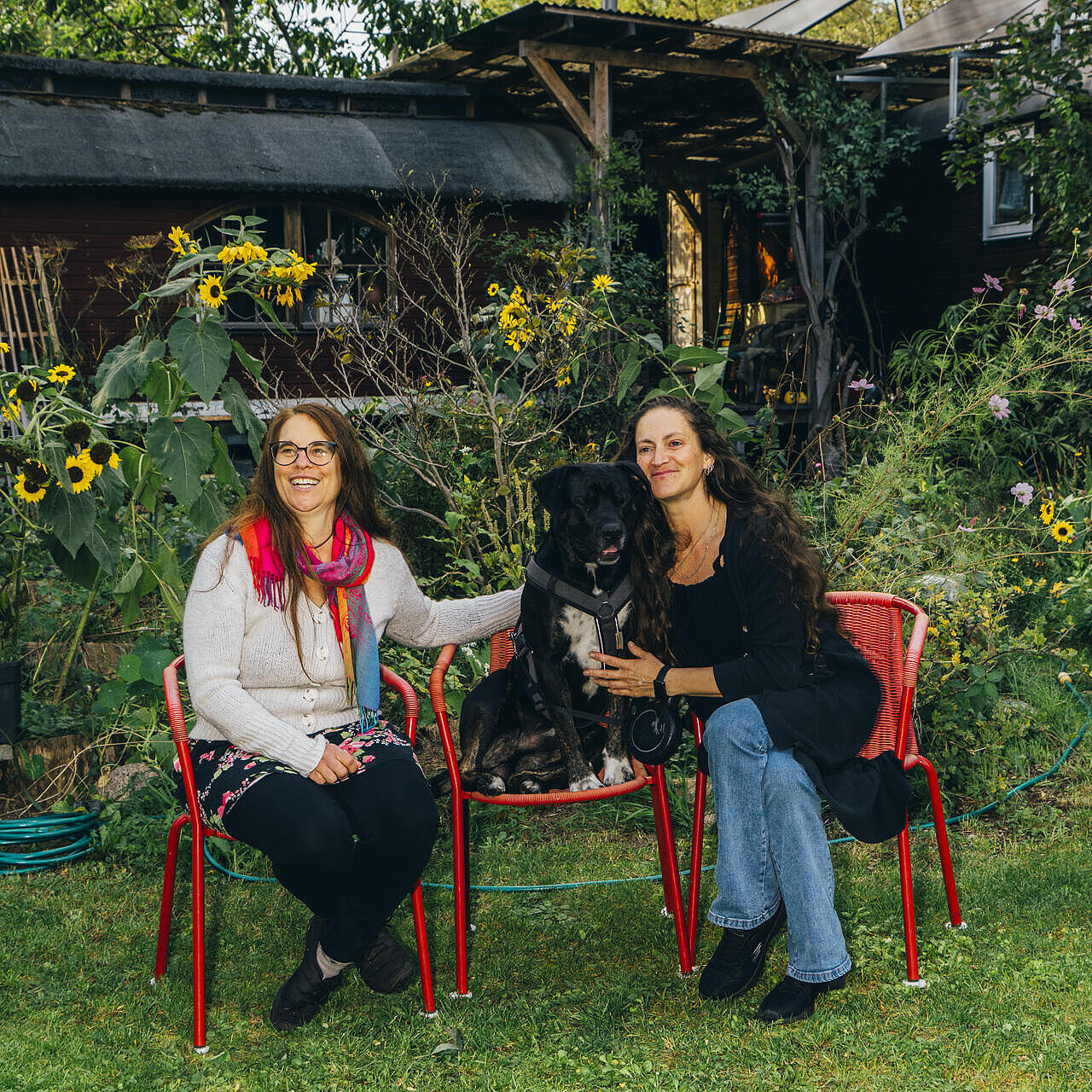 Irina und Martina sitzen mit Hund im Garten