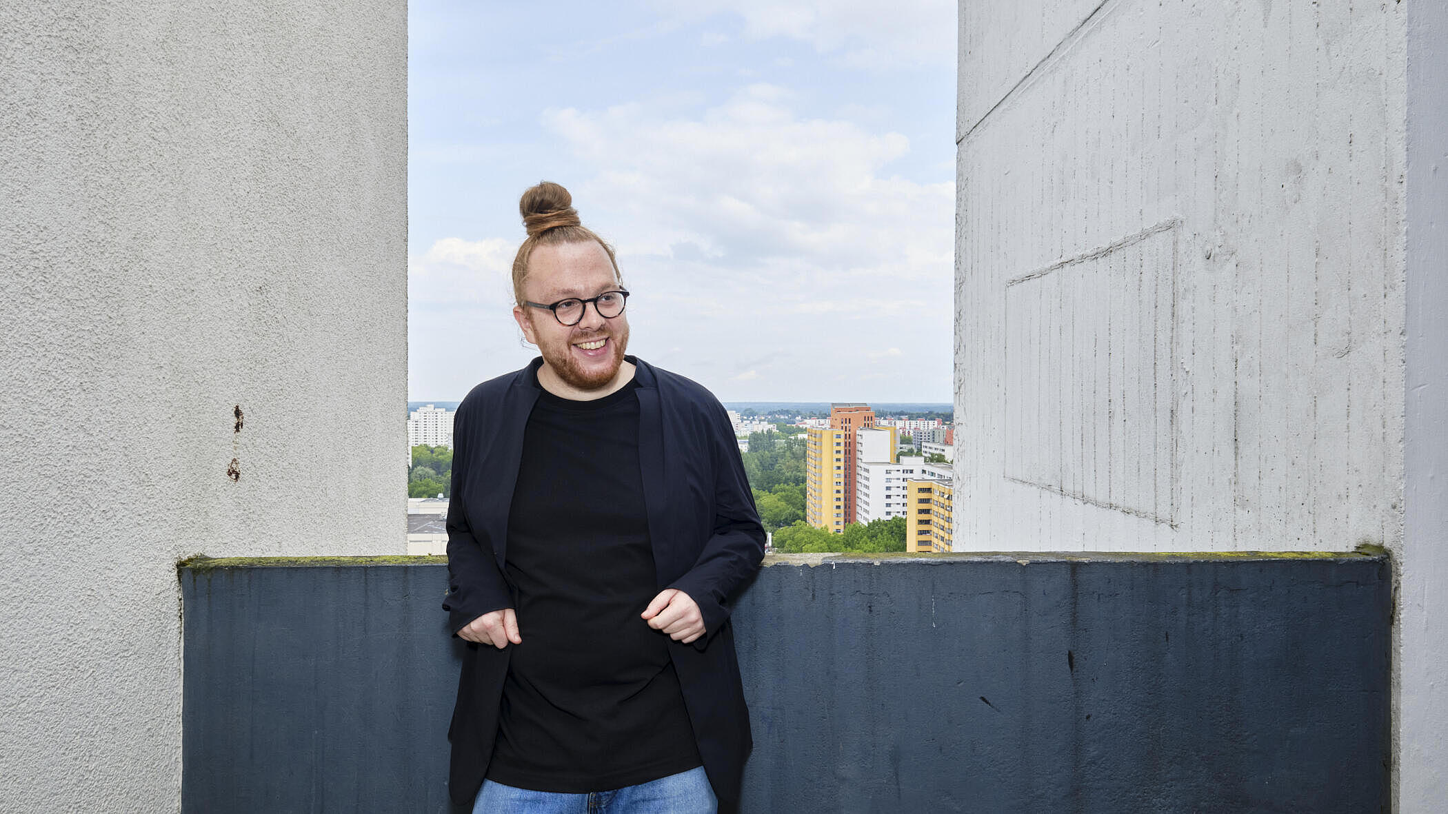 Ole Buchwaldt steht auf einem Balkon, im Hintergrund die Häuser des Märkischen Viertels