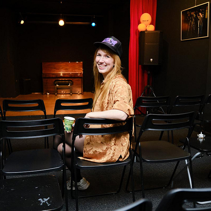 Christin Nichols sitzt auf einem Stuhl vor der Bühne