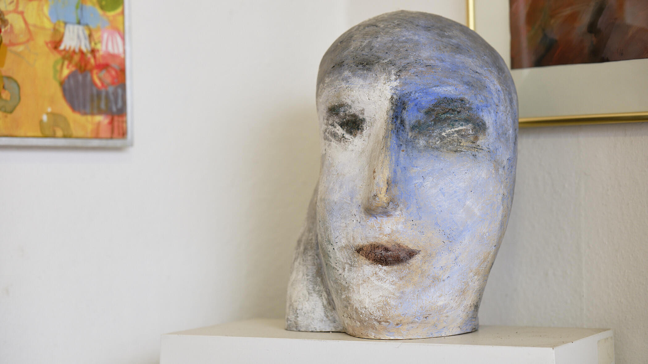 Ein Kopf aus Keramik in weiß, grau und blau in einer Raumecke