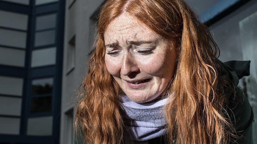 Anna Scheld hält ihre Hand zum Schutz vor ihrem Körper. Ihr Gesichtsausdruck zeigt Angst