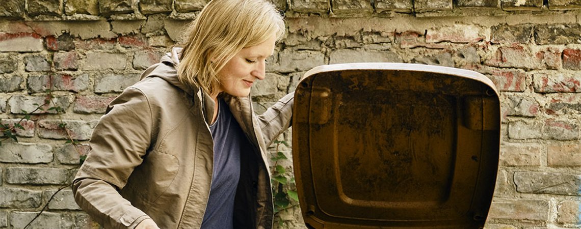 Eine Frau entsorgt Müll in der Mülltonne