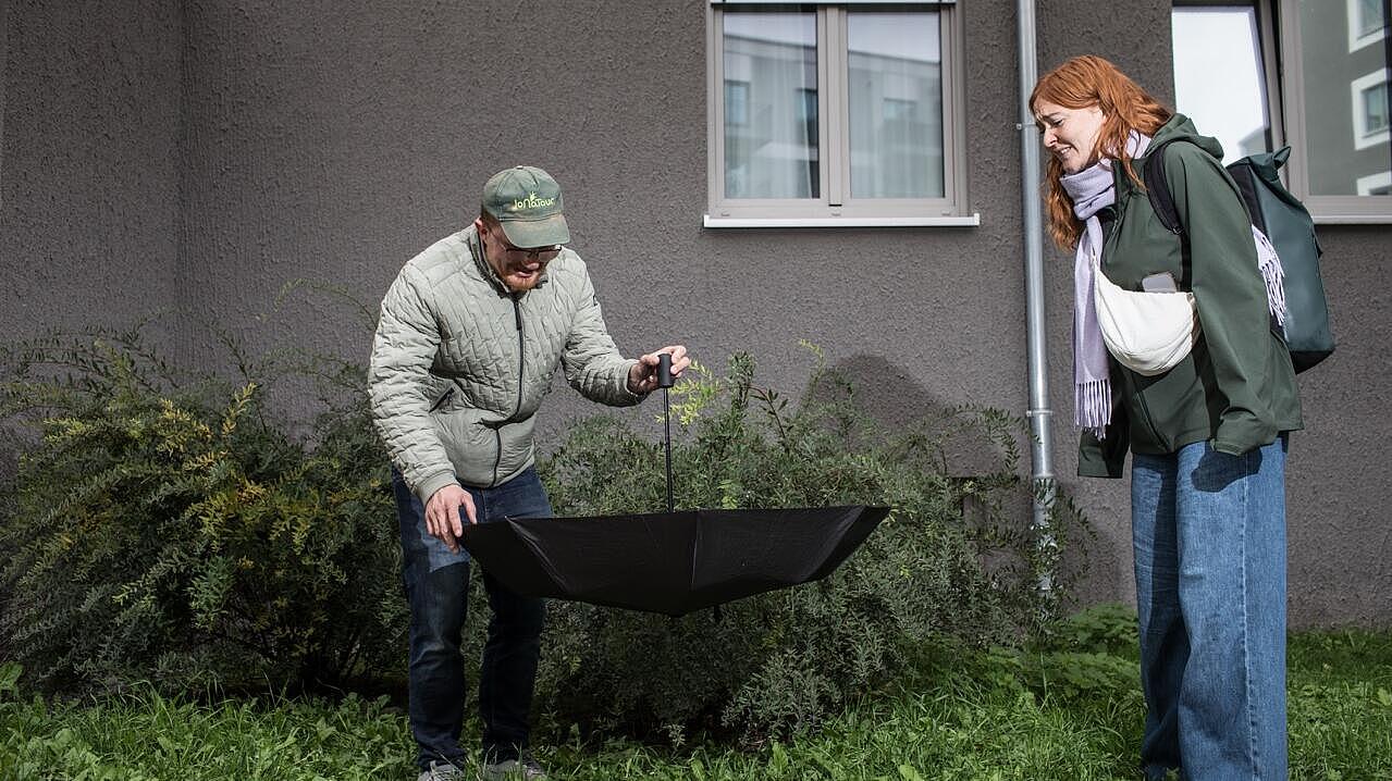 Anna Scheld steht mit Abstand zum Tourguide der in einem Regenschirm Spinnen fängt