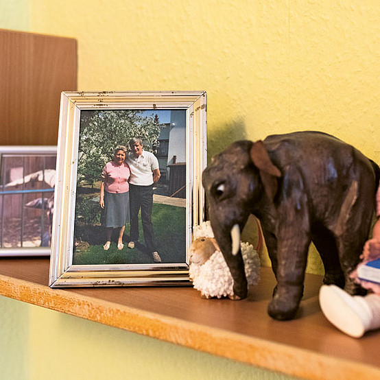 Auf den Regalen stehen persönliche Gegenstände des Ehepaars, darunter ein altes Foto der beiden in ihrem Garten