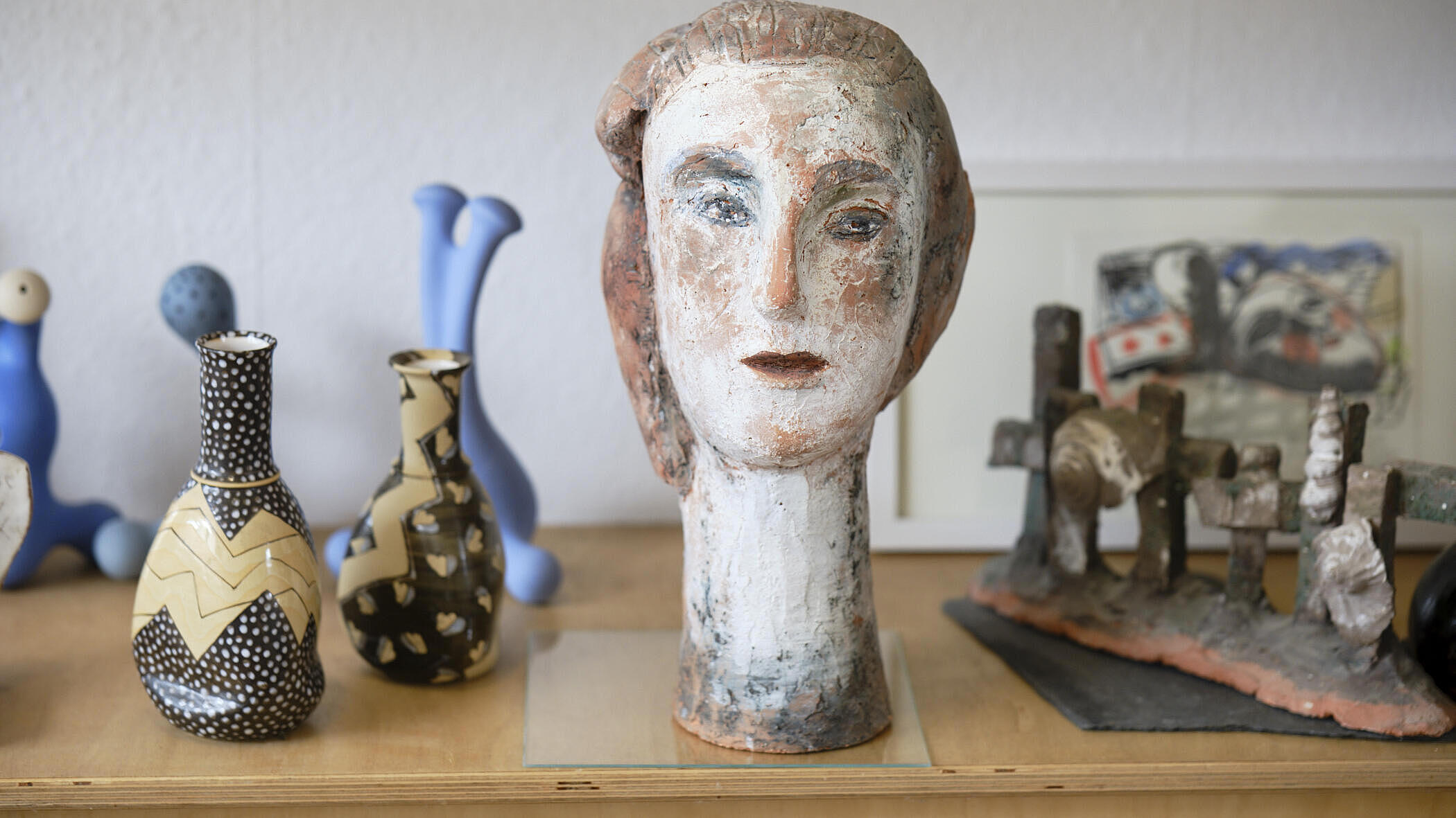 Eine Statue eines weiblichen Kopfes inmitten weiterer Keramik