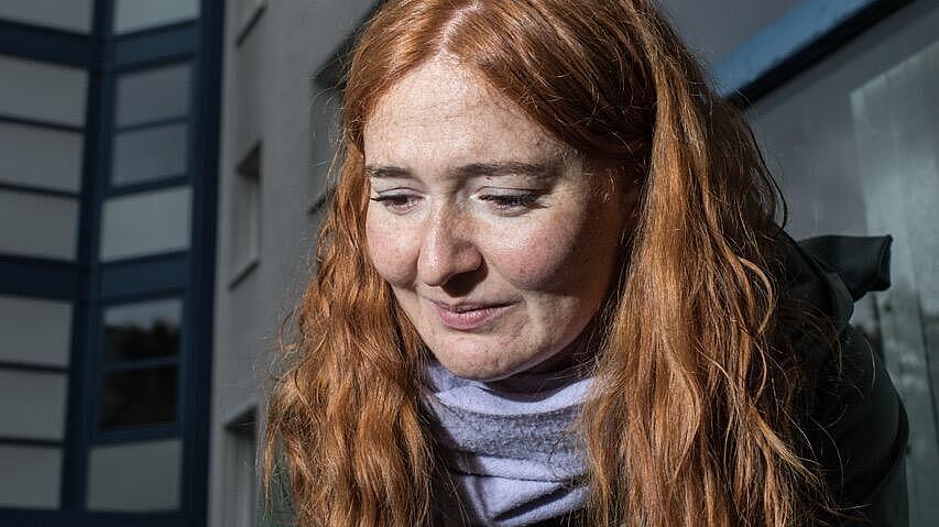 Autorin Anna Scheld greift mit neugierigem Gesicht nach etwas außerhalb des Bildes