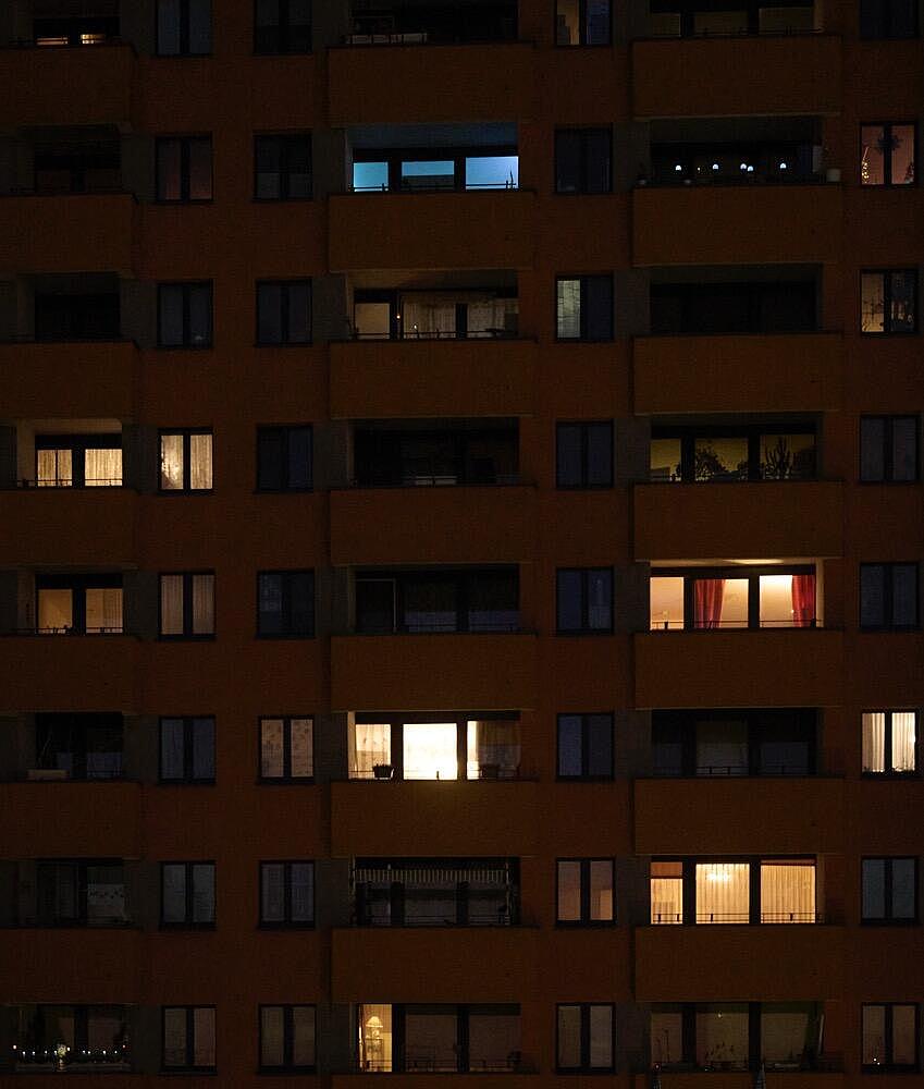 Hausfassade bei Nacht mit vielen beleuchteten Wohnungen